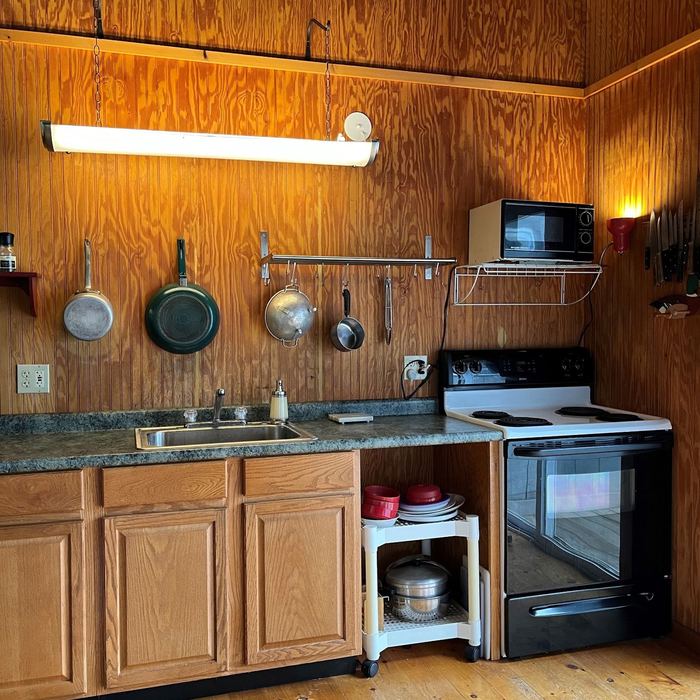Cabin kitchen with stove, sink and hanging pans